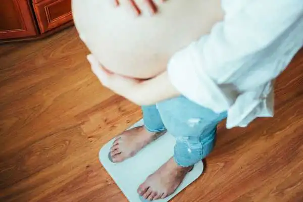 Image of woman weighing herself and experiencing weight gain through pregnancy Gorgie